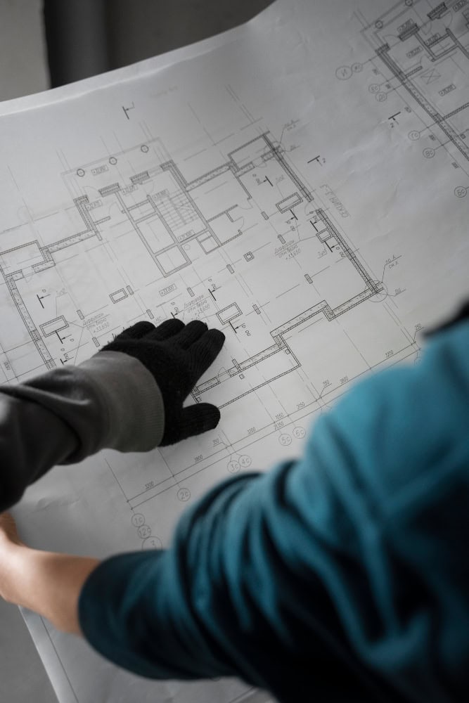 Profesional revisando planos arquitectónicos sobre una mesa, representando la planificación y coordinación de reformas integrales de viviendas en Madrid.